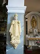 Une statue de l'Enfant Jésus de Prague. À droite la chapelle de la Vierge-Marie.