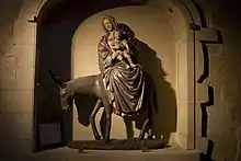 Vue en clair obscure d’un groupe statuaire représentant un âne portant un homme et un enfant.