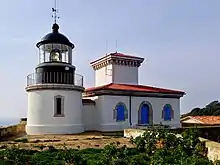 Photographie en couleur d'un phare avec son bâtiment attenant pour les gardiens.