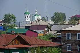 Vue du centre de Ienisseïsk avec des bâtiments en bois et la cathédrale de l'Épiphanie en fond.