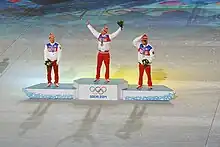 Vue de loin du podium des 50 kilomètres des Jeux de Sotchi, le vainqueur levant les bras en l'air.