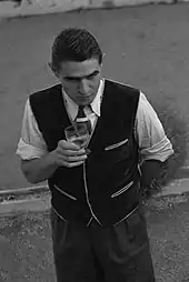 Photographie en noir et blanc d'un homme tenant un verre dans sa main.