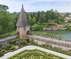 Tour à toit pointu en brique à l'angle d'une promenade sous pergola. En arrière-plan, le quartier de la Madeleine sur la rive droite du Tarn s'étage au dessus de jardins suspendus.