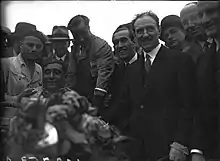 Photo de groupe regroupant hommes en tenue de ville, pilote et mécaniciens.
