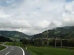 Vue depuis la route de Leogang avec la cheminée de l'usine d'extraction de magnésite et la ligne de chemin de fer.