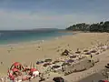 La plage de Trestraou en saison touristique ; au large l'Île Tomé).