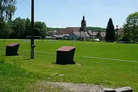 Un terrain de foot avec le village et le clocher à l'arrière-plan.