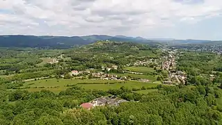 Une colline boisée derrière laquelle s'étendent des montagnes.