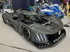 Photo du dessus d'une voiture de course grise et noire sur un stand d'exposition.