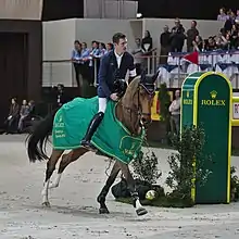 Cavalier galopant dans un décor avec de nombreux logos de Rolex