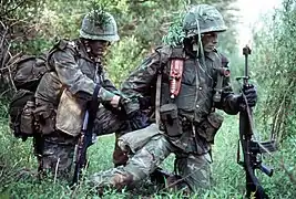 Vue rapprochée d'un aspirant officier des Marines prêt au combat qui vérifie le sac à dos d'un autre aspirant. Tous deux portent de la peinture de camouflage sur le visage. Les marines sont des élèves de l'école de base pour l'entraînement au combat des officiers de marine.