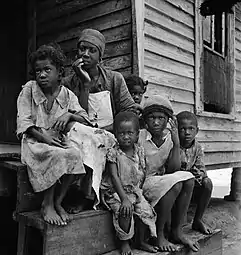 « Un dollar par jour. Famille d'un travailleur de la térébenthine près de Cordele, en Alabama. Le salaire du père est d'un dollar par jour. C'est le niveau de vie que ces gens là supportent ». Juillet 1936.
