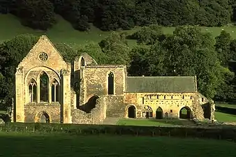 Vue générale d'un monastère partiellement ruiné, dont l'aile perpendiculaire à l'église est mieux conservée.