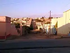 Rue principale goudronnée à l'avant-plan et route secondaire en terre.