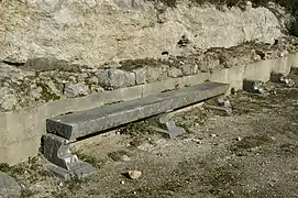 Banc, le long de la paroi arrière de la stoa.
