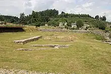 Photographie en couleurs de vestiges de murs au milieu d'un champ.