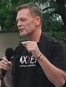 Photo en couleur d'un homme aux cheveux courts châtains parlant dans un micro