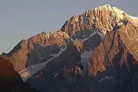 Le mont Blanc de Courmayeur au lever du soleil depuis l'est avec la pointe Innomée éclairée au centre, encadrée par l'arête du Brouillard à gauche et les aiguilles de Peuterey à droite.