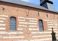 Le mur sud de la nef, dont l'appareil est constitué d'une alternance de pierre calcaire et de brique, porte la date de 1699.