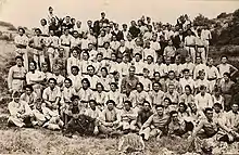 Photo de groupe de militaires, la majorité en tenue de service en toile claire, certains en uniforme kaki ou bleu horizon. Deux mulets participent à la photo, cachés parmi les soldats.