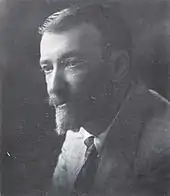 Photo en noir et blanc montrant un homme avec une moustache et un bouc