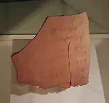 Fragment de poterie portant une inscription peinte à demi effacée.