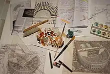 Photographie de divers outils d'aquarelliste : palette, peinceaux, brosses, papier à dessin.