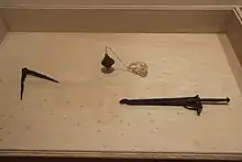 Trois outils dont un compas présentés dans une vitrine.