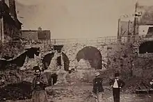 Photographie ancienne figurant un chantier et des personnages au premier plan.