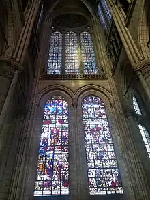 Vue en contre-plongée d'un mur percé de fenêtres, de trois verrières décoratives et de deux grandes verrières figuratives.