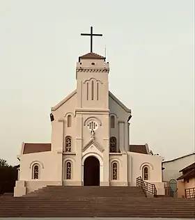 Plusieurs dizaines de personnes devant une église aux tons jaunes.