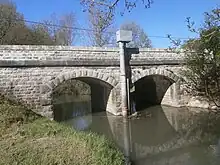 Photographie en couleurs d'un pont à deux arches enjambant un cours d'eau.
