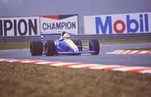 Photo d'une monoplace blanche et bleue sur une piste mouillée