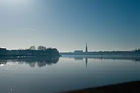 Photographie large de la Garonne avec un grand ciel bleu. On aperçoit la ville en fond.