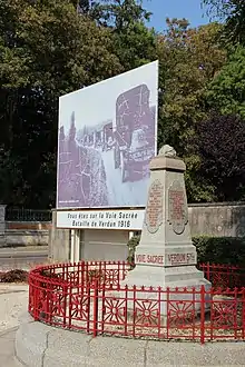 Photographie d'un monument en pierre et d'un grand panneau routier montrant une photo de camions.