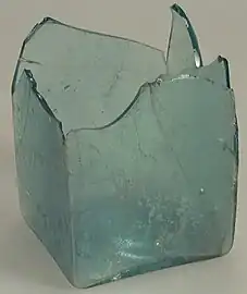 Bouteille carrée de teinte bleu-vert naturel, à fond carré. Fragmentaire.