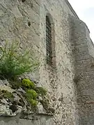 Mur de l'église présentant des ouvertures étroites typiques des églises du XIIIe siècle.