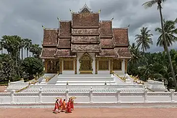 Moines bouddhistes marchant devant le temple Haw Pha Bang