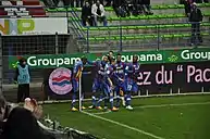 Photographie de joueurs de football célébrant un but au poteau de corner.