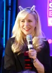 Femme aux cheveux blonds avec une veste noire.