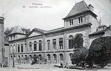 Phototyoie d'un bâtiment de deux étages du début du XXe siècle. Au centre fronton au-dessus de deux fenêtres, deux ailes de trois fenêtres et à chaque extrémité surélévation d'un étage au-dessus d'un corps de bâtiment à deux fenêtres.
