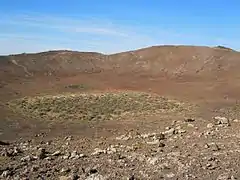 Vue du cratère avec un îlot de végétation arbustive épineuse.