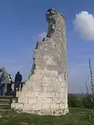 Photographie en couleurs d'un ancien moulin dont il ne reste qu'une portion de mur courbe.
