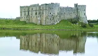 Photo d'un bâtiment imposant aux murs épais se reflétant dans un plan d'eau