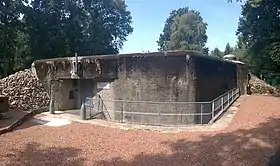 La façade arrière de la casemate, avec la porte blindée et le fossé diamant. La cloche GFM est visible à l'arrière-plan.