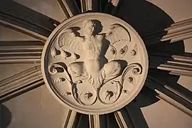 Photographie en couleurs d'un élément sculpté d'un escalier ancien.