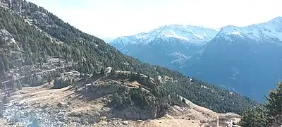 Photographie de l'Arcelin, de ses alentours de forêt, sa chapelle Notre-Dame-des-Anges et les montagnes enneigées ; la chapelle et son lieu-dit dominent la vallée plus bas.