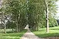 Perspective du château au fond de l'allée bordée d'arbres.
