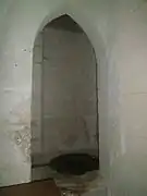 Photographie en couleurs d'une niche dans un mur et dont le sol est recouvert d'une grille.