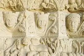 Photographie en couleurs de bas-reliefs représentant des figures humaines encadrées de motifs végétaux.
